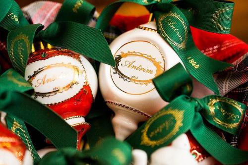 A close-up of decorative ornaments with green ribbons, featuring the name "Antrim" in gold lettering.