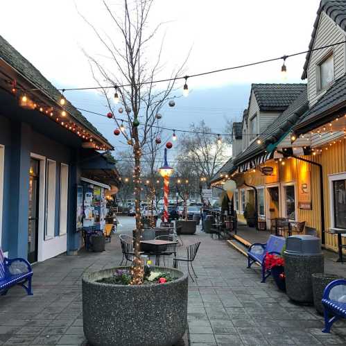 A charming street scene with shops, string lights, and a decorated tree in a cozy, inviting atmosphere.