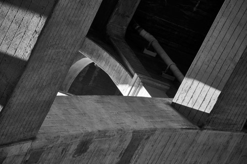 Abstract black and white image of concrete structures with shadows and light creating geometric patterns.