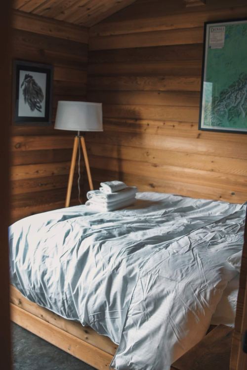 Cozy bedroom with a wooden interior, featuring a neatly made bed and a lamp beside it.