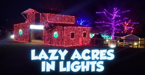 A brightly lit barn decorated with colorful lights, surrounded by illuminated trees, with the text "Lazy Acres in Lights."