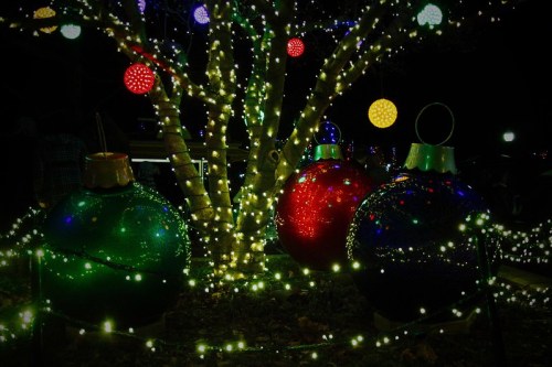 Colorful Christmas ornaments and twinkling lights on a tree, creating a festive holiday atmosphere.