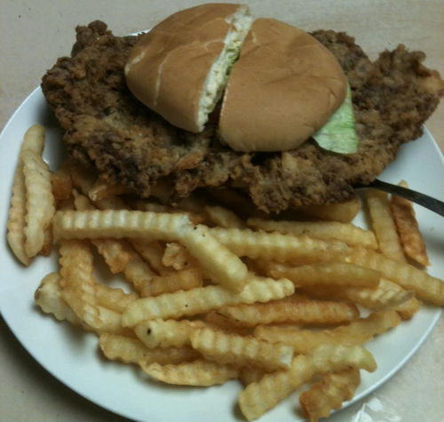 A plate of crispy fried chicken, a sandwich with lettuce, and a side of crinkle-cut fries.