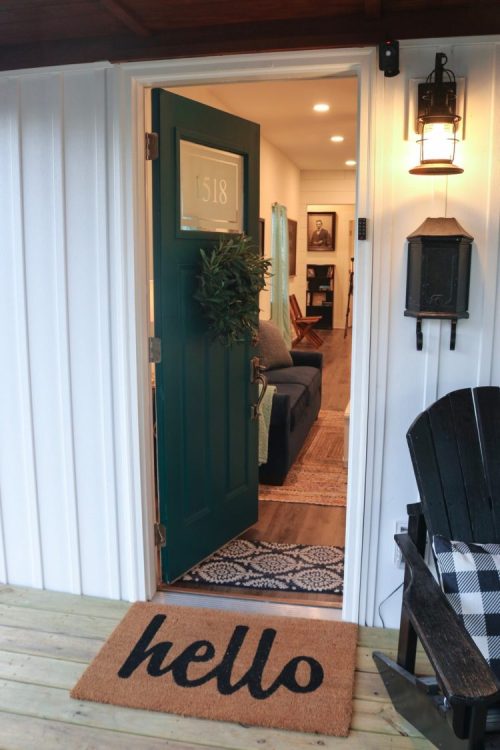 A welcoming front door with a green door mat that says "hello," leading into a cozy, well-lit interior.
