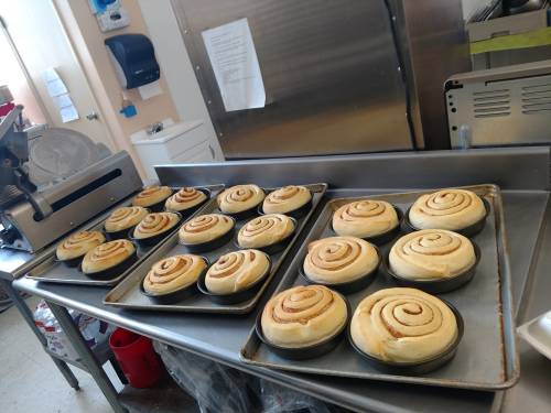 Freshly baked cinnamon rolls on trays in a kitchen, ready for serving.