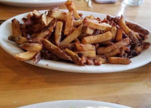 A large plate of golden-brown French fries piled high on a wooden table.