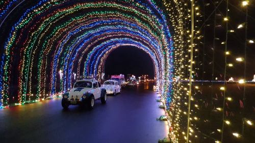 A colorful tunnel of lights with cars driving through, creating a festive and vibrant atmosphere.