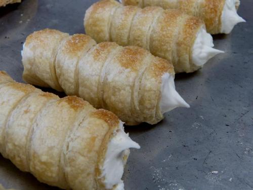 Close-up of pastry rolls filled with cream, arranged neatly on a silver tray.