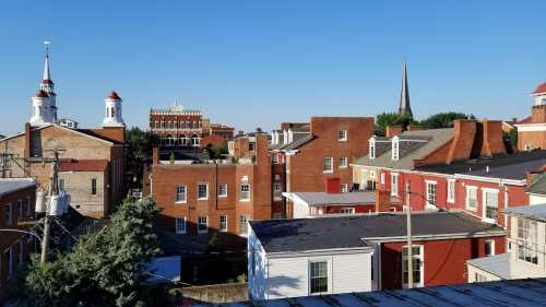 A scenic view of a historic town with red brick buildings, steeples, and a clear blue sky.
