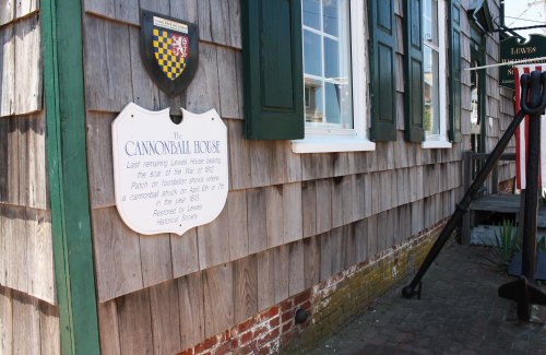 Sign for the Cannonball House, a historic building with wooden siding and green shutters, featuring a coat of arms.