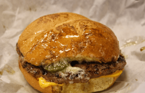 A close-up of a cheeseburger with melted cheese, pickles, and a shiny, toasted bun.