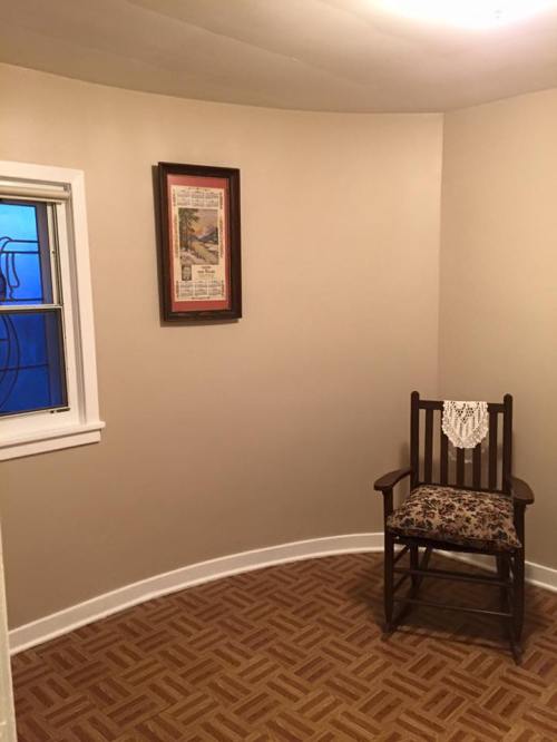 A cozy corner of a room featuring a wooden rocking chair and a framed picture on the wall.