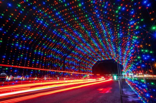 A colorful tunnel of lights with red, blue, and green bulbs, creating a festive atmosphere at night.
