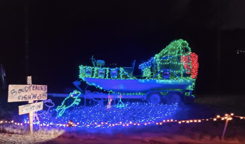 A brightly lit boat decorated with colorful lights, surrounded by festive decorations at night.