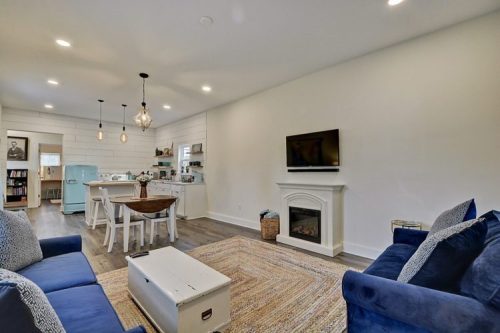 Cozy living room with blue sofas, a white fireplace, a dining area, and a vintage fridge in a bright, modern space.
