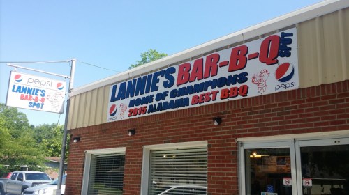 Sign for Lannie's Bar-B-Q, featuring "Home of Champions" and "2015 Alabama Best BBQ," on a brick building.