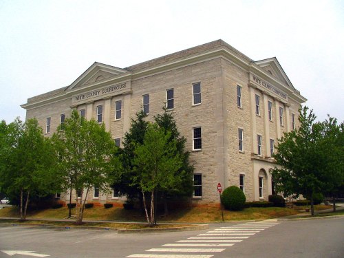 Historic White County Courthouse with stone facade and surrounding greenery, viewed from the street.