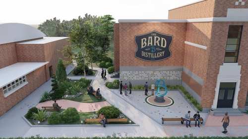 Aerial view of Bard Distillery featuring a brick building, outdoor seating, and landscaped gardens with visitors.