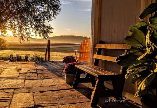 A serene sunrise view from a porch, featuring a wooden bench, potted plants, and a misty landscape in the background.