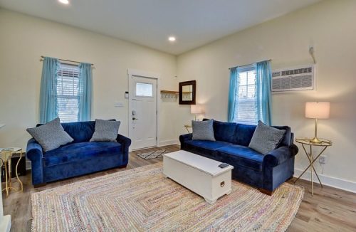 Cozy living room with two blue sofas, a white coffee table, and light curtains, featuring a welcoming entrance.