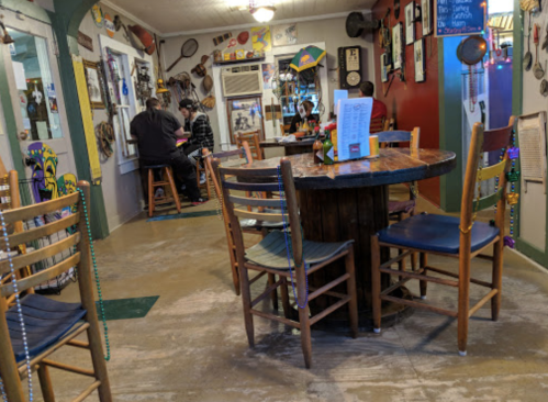 A cozy restaurant interior with colorful decor, wooden tables, and chairs, featuring patrons dining in the background.
