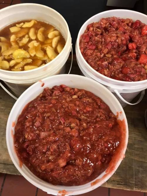 Three white buckets filled with different fruit mixtures: one with apple slices, and two with strawberry mixtures.