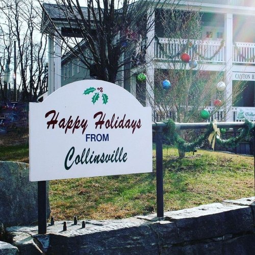 A sign reading "Happy Holidays from Collinsville" in front of a building decorated for the holiday season.