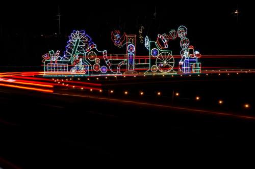 Colorful holiday light display featuring various festive shapes and designs against a dark night sky.