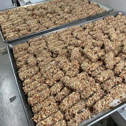 Trays filled with neatly arranged, nut-covered snack bars ready for packaging or serving.