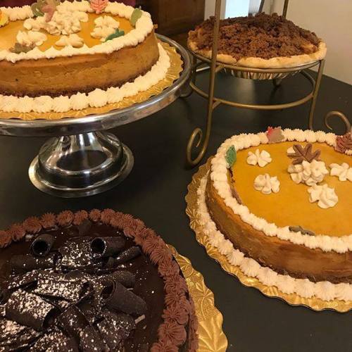 Three delicious desserts: a pumpkin pie, a chocolate cake with curls, and a crumb-topped pie on a decorative stand.