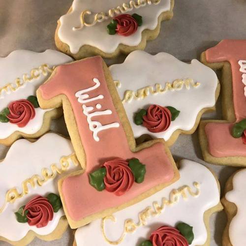 Decorated cookies featuring the number "1," roses, and the name "Cameron" in elegant icing.