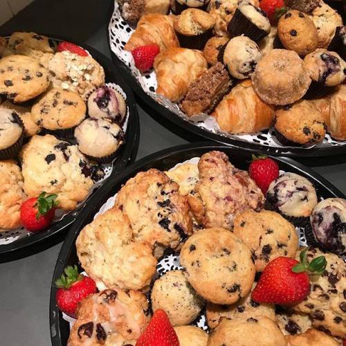 A variety of muffins and pastries arranged on plates, with fresh strawberries for garnish.