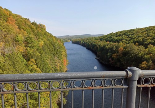 A scenic view of a river winding through lush green hills, framed by a decorative metal railing.