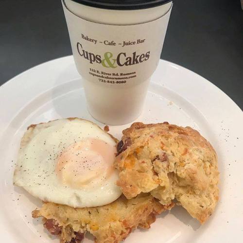 A plate with a biscuit, a fried egg, and a coffee cup from Cups & Cakes bakery.