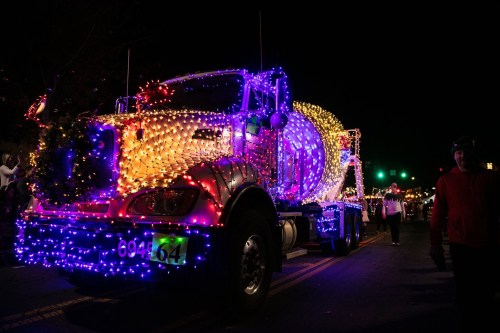 A brightly lit truck decorated with colorful lights, part of a festive parade at night.
