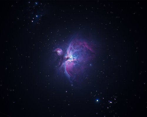 A vibrant nebula with swirling colors of purple, blue, and pink against a dark starry background.