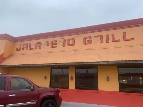 Exterior of Jalapeño Grill restaurant with a bright orange facade and a red truck parked in front.