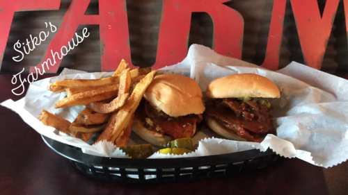Two delicious sandwiches with fries and pickles in a basket, set against a rustic background with "Farm" lettering.