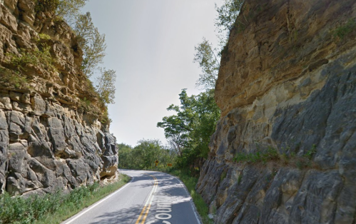 A winding road surrounded by steep rock formations and greenery on either side.