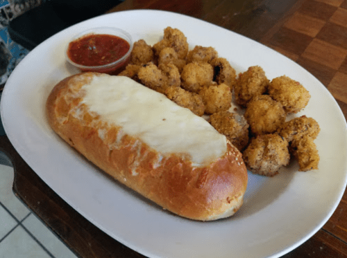 A plate with a cheesy bread roll, marinara sauce, and a side of golden-brown breaded bites.