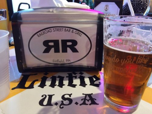 A table setting at Railroad Street Bar & Grill in Linfield, PA, featuring a beer and a menu holder.