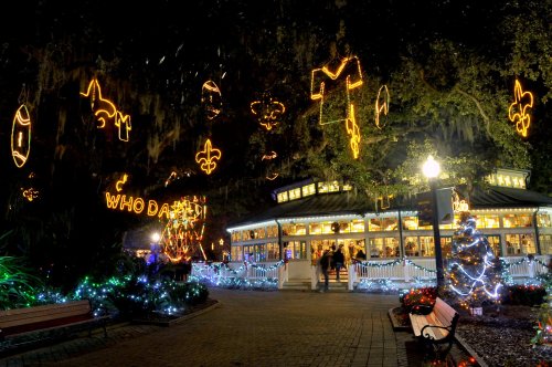 A festive park at night, adorned with colorful lights, including a Christmas tree and holiday decorations.