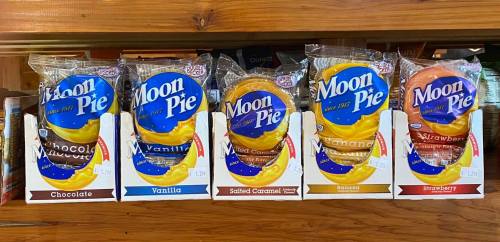 A shelf displaying various flavors of Moon Pie: Chocolate, Vanilla, Salted Caramel, Banana, and Strawberry.
