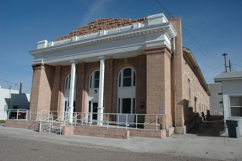 Historic building with a stone facade, large columns, and a ramp, set against a clear blue sky.