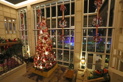 A beautifully decorated lobby with a large Christmas tree and festive wreaths, illuminated by soft lights.