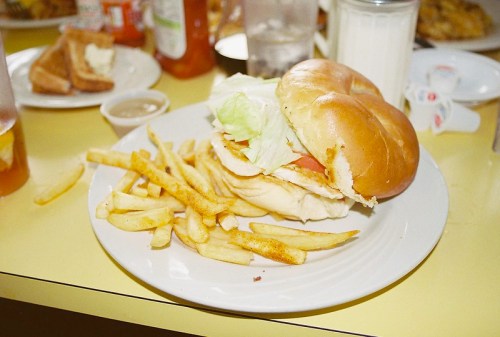 A plate with a sandwich featuring lettuce and tomato, accompanied by a side of French fries.