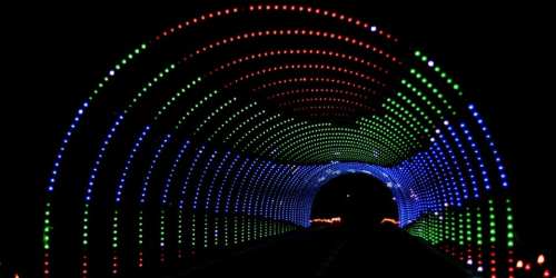 A colorful illuminated tunnel with vibrant green, red, and blue lights creating a dynamic pattern against a dark background.