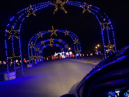 A nighttime scene of a road illuminated by blue and yellow star-shaped lights, creating a festive atmosphere.