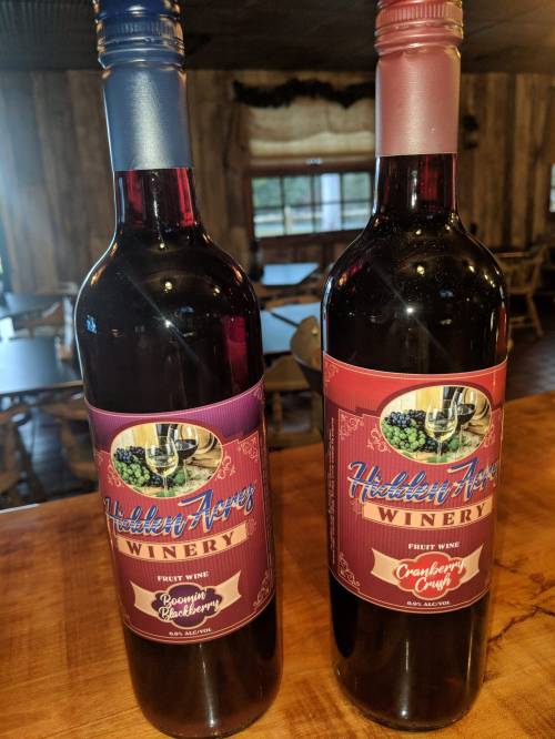 Two bottles of wine from Hidden Acres Winery, labeled "Raspberry Blackberry" and "Cranberry Crush."