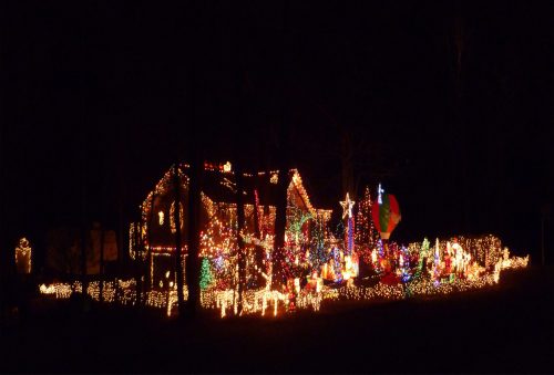 A brightly lit house decorated with colorful Christmas lights and festive displays in a dark night setting.